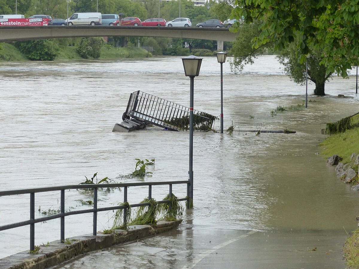 A road submerged under floodwater with a partly buried fence line